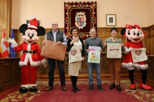 Personas en evento navideño con personajes disfrazados y materiales de campaña