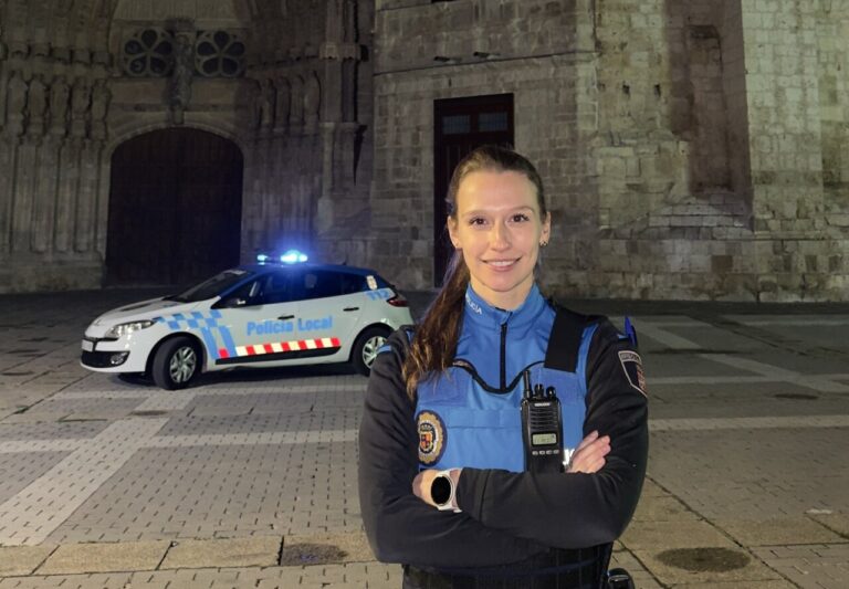 Agente de policía local sonriendo frente a un coche patrulla en Palencia