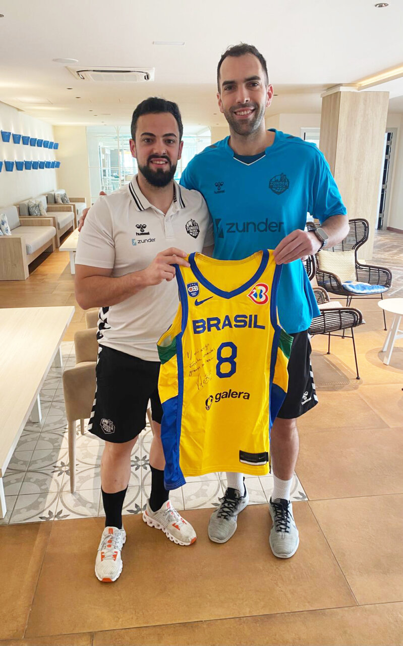 Dos hombres sosteniendo una camiseta de baloncesto de Brasil en una clínica.