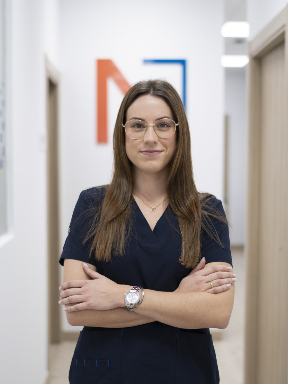 Mujer con uniforme de clínica dental sonriendo en un consultorio moderno