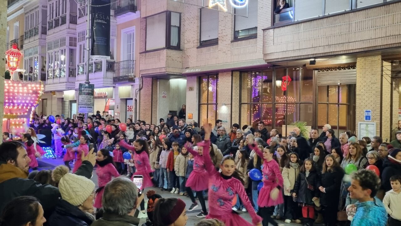 Desfile navideño en Palencia con bailarinas y una multitud de espectadores.
