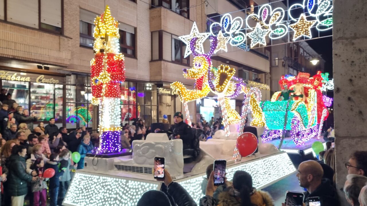 Desfile navideño con luces brillantes y personas en la calle