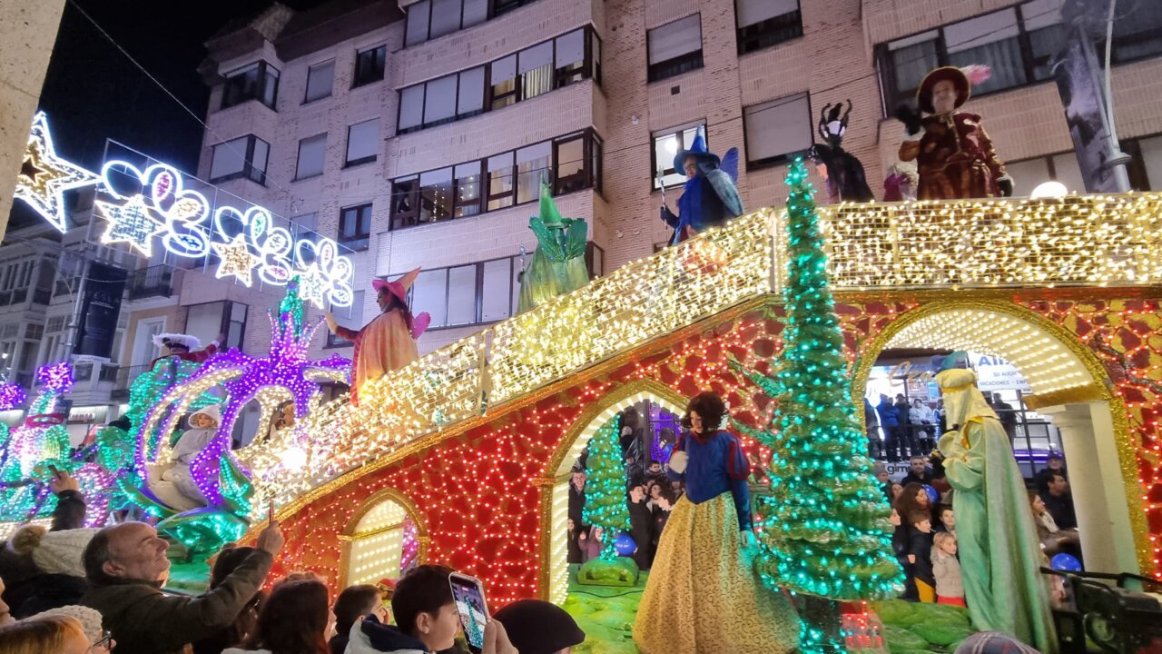 Desfile navideño con personajes de cuentos y luces brillantes.