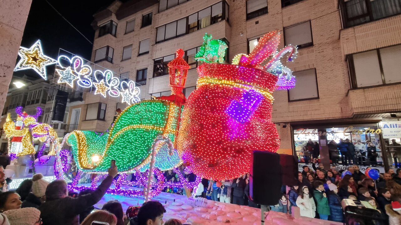 Carroza iluminada en un desfile navideño con multitudes