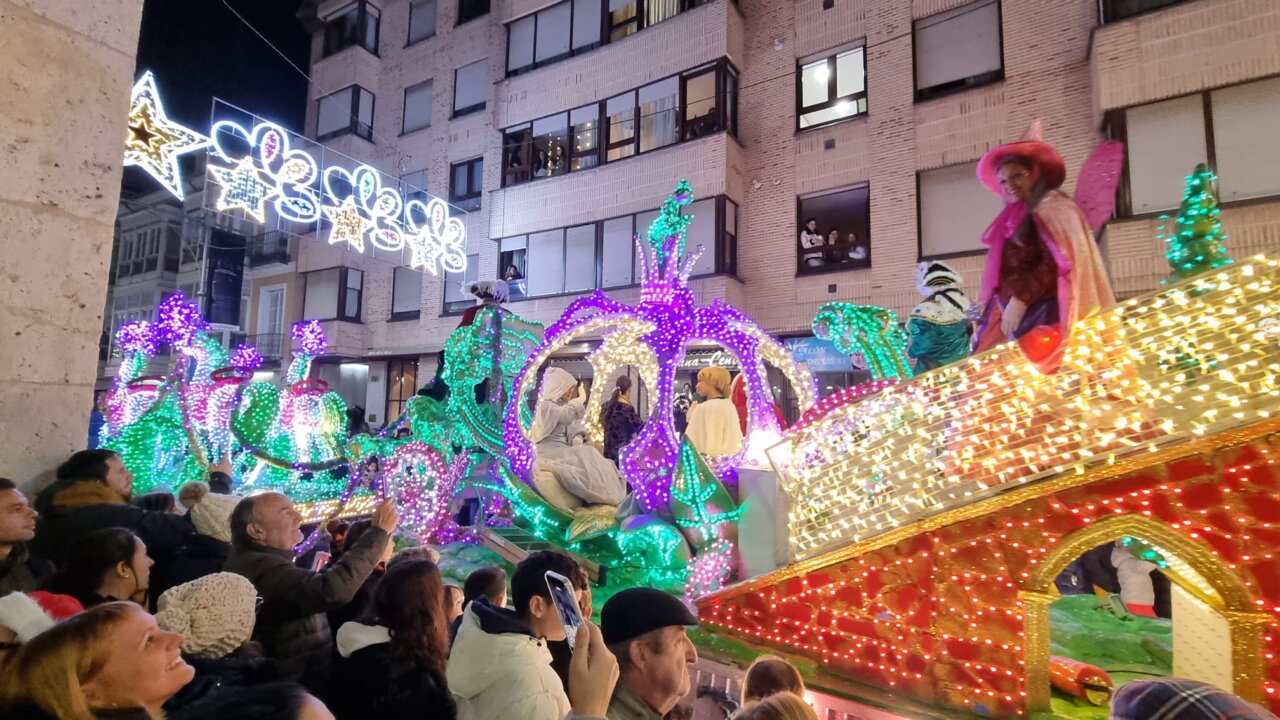 Desfile navideño con carrozas iluminadas y espectadores emocionados.