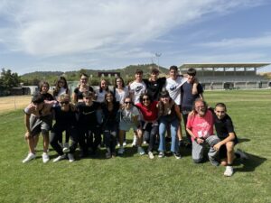 Grupo de estudiantes sonrientes en un campo de deportes.