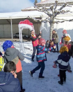 Niños celebrando en la nieve durante una fiesta navideña en Villamanín