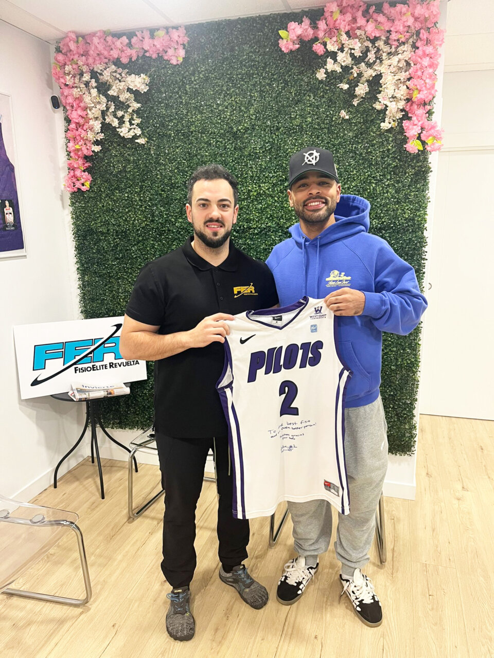 José Daniel Revuelta y jugador sosteniendo camiseta en clínica FisioÉlite Revuelta