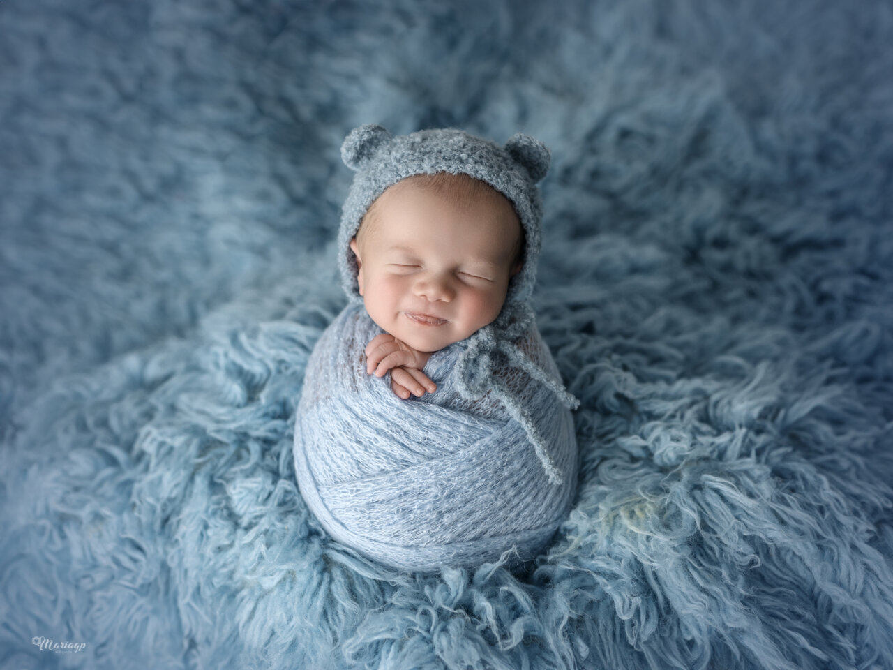 Bebé sonriente envuelto en una manta azul suave