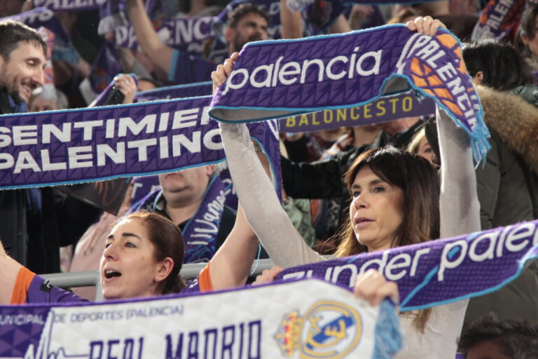 Aficionados animando al Súper Agropal Palencia con bufandas en un partido.