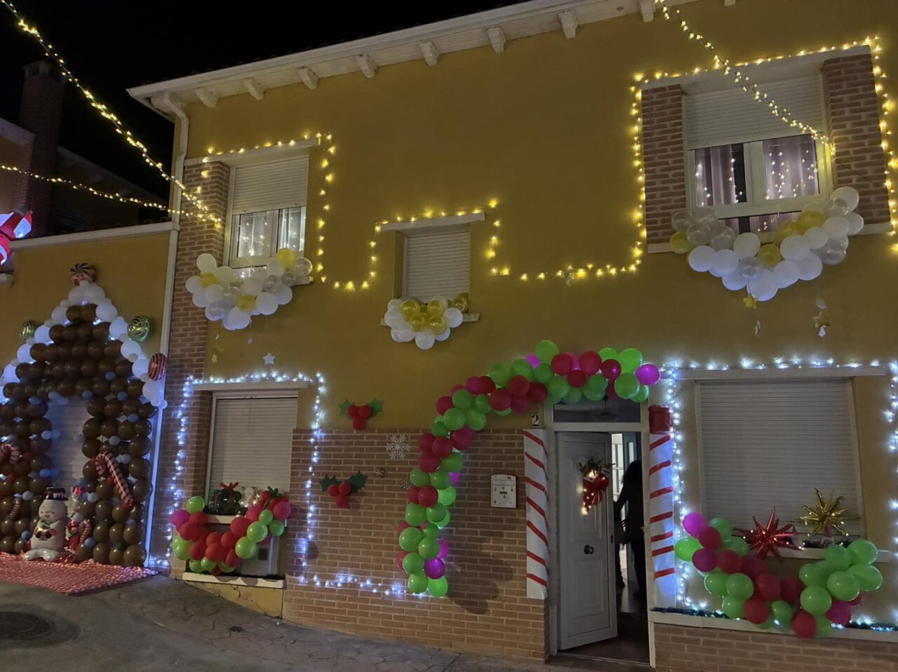 Fachada decorada con luces y globos navideños en Grijota