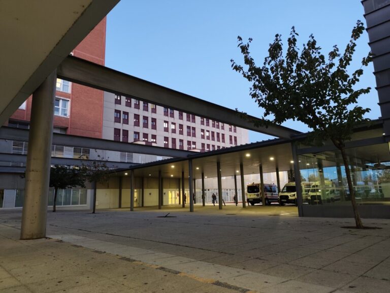 Vista exterior del Hospital de Palencia al atardecer con vehículos de emergencia.