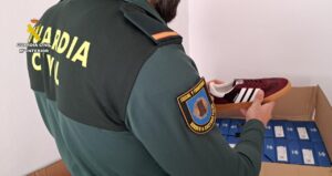Agente de la Guardia Civil revisando zapatillas falsas en una caja