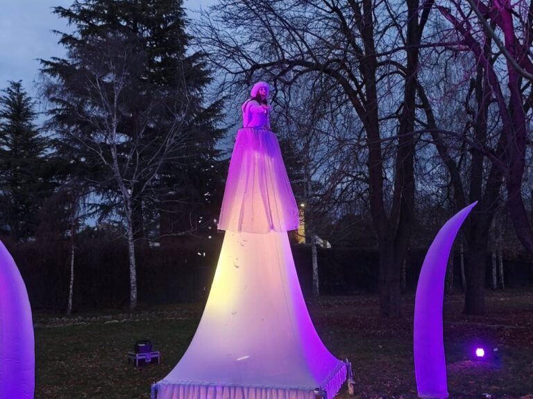 Escenario del Jardín de la Fantasía con figura iluminada en vestido blanco