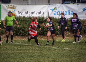 Jugadora sub-14 en un partido de rugby intentando alejar a un contrincante