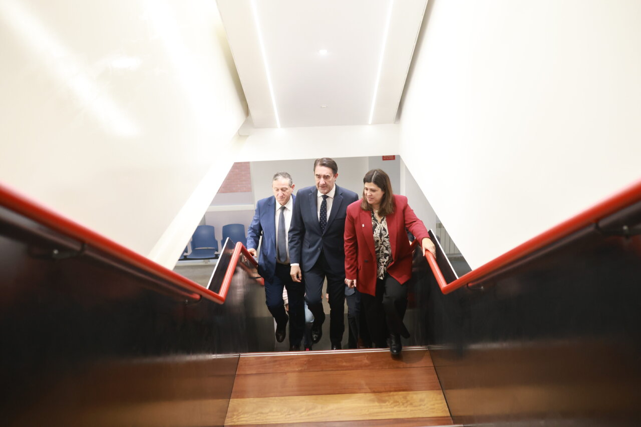 Tres personas bajando una escalera en un edificio oficial