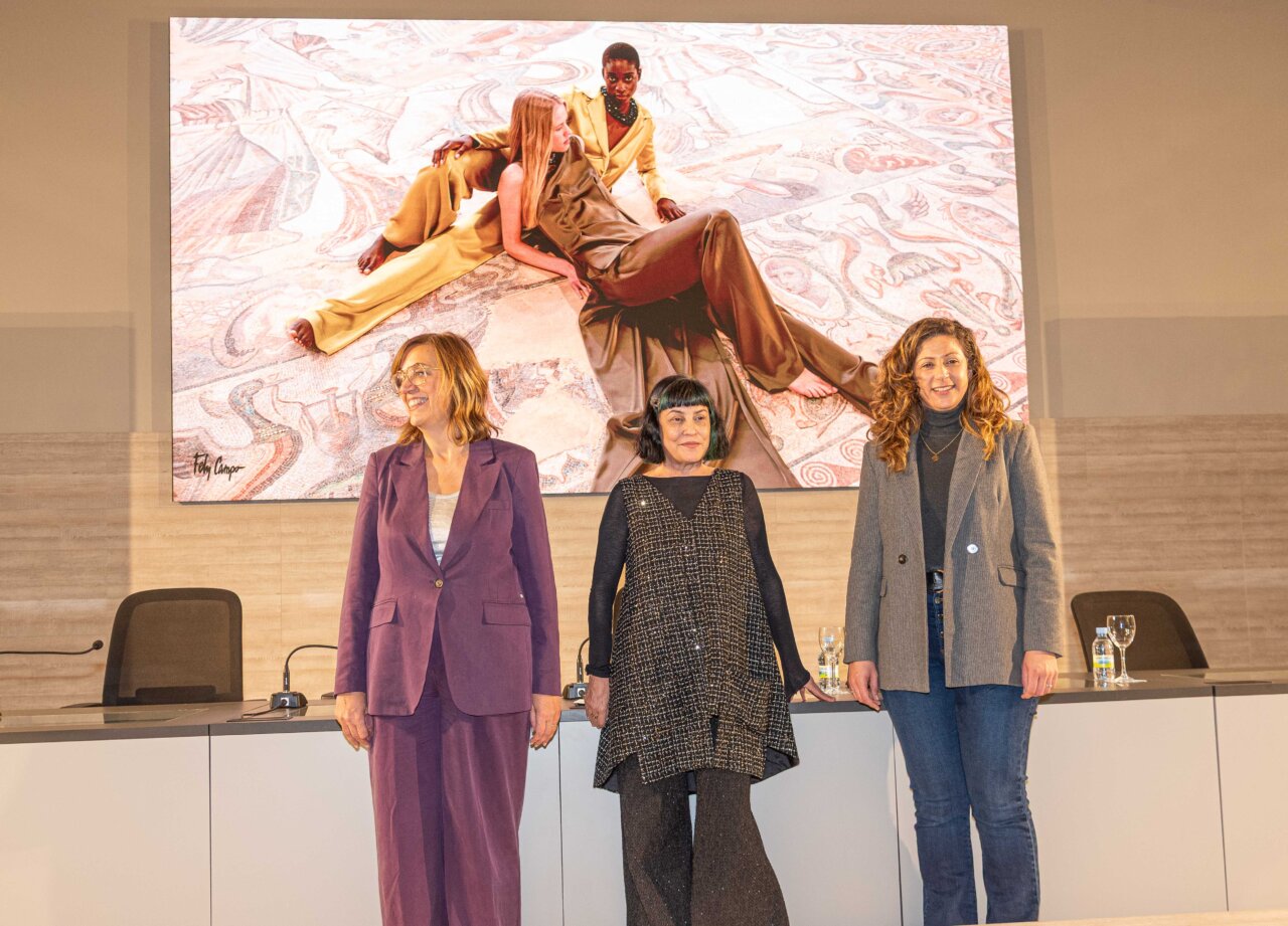 Tres mujeres posando en un evento de moda con un fondo artístico