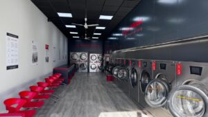 Interior de la lavandería Speed Queen con máquinas modernas y sillas rojas