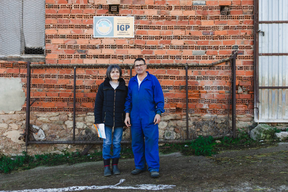 Dos personas junto a un edificio con el logo de IGP Lechazo de Castilla y León