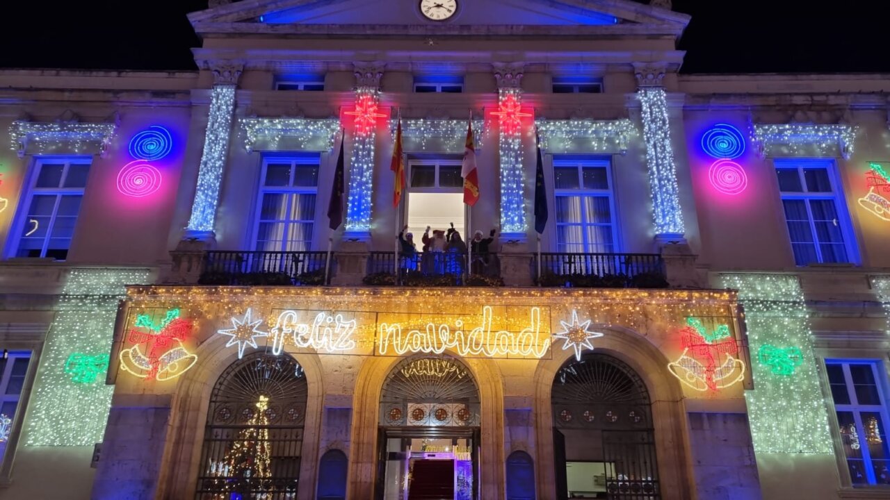 Edificio iluminado con decoraciones navideñas y mensaje de feliz navidad