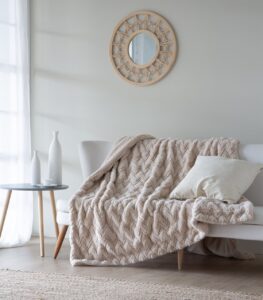 Manta suave y acogedora sobre un sofá con cojín y mesa