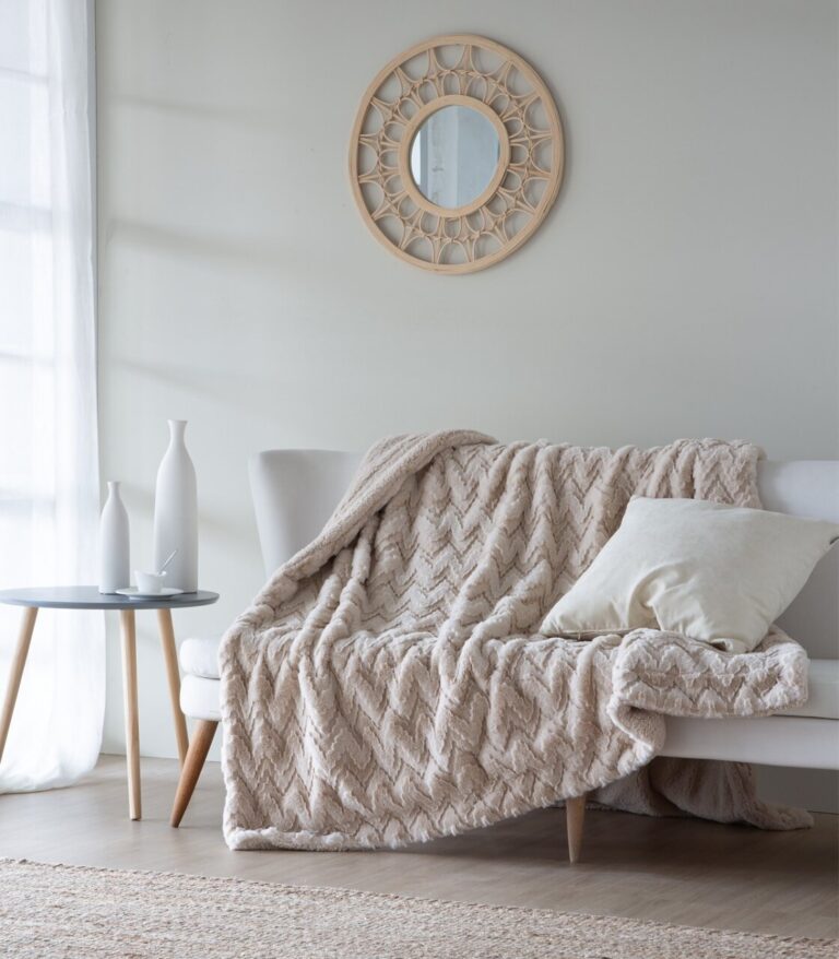 Manta suave y acogedora sobre un sofá con cojín y mesa