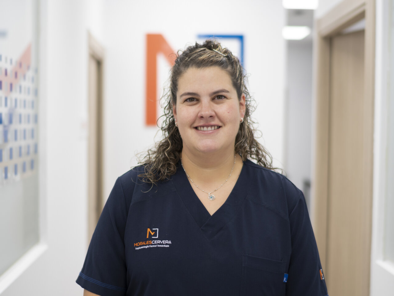 Mujer sonriente en uniforme de clínica dental en un entorno profesional