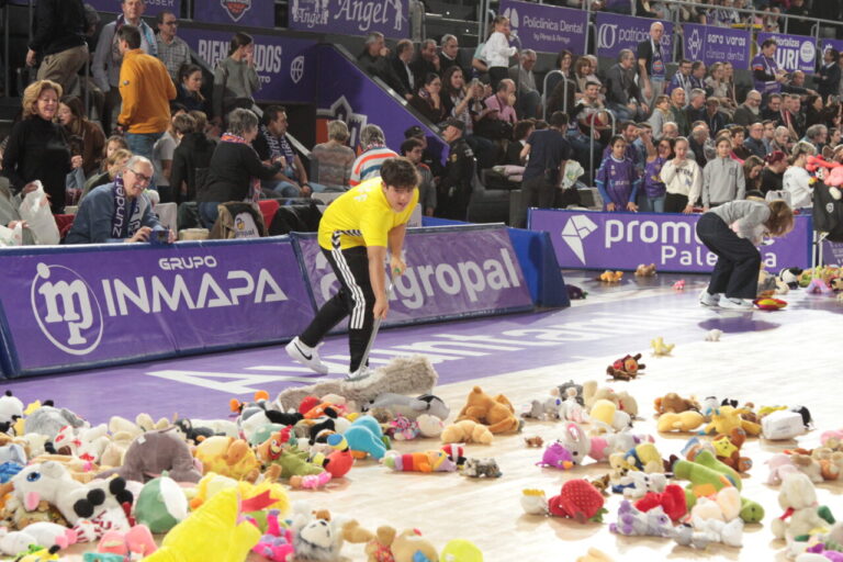 Jugadores recogen peluches en la cancha durante el evento navideño