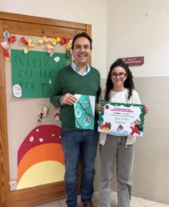 Nadia Paredes sosteniendo un diploma junto a un hombre en un evento navideño