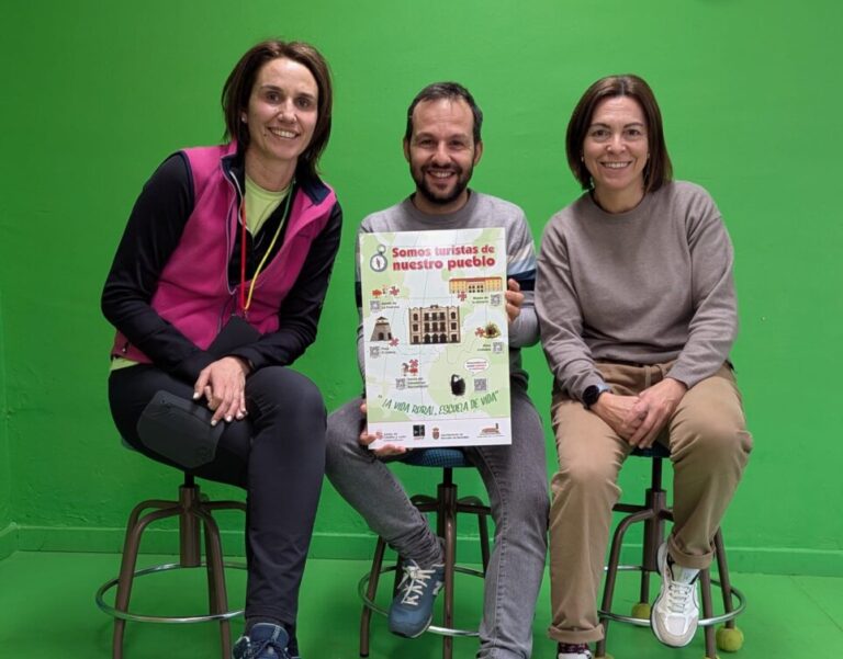 Tres personas posando con un cartel del proyecto escolar en un fondo verde.