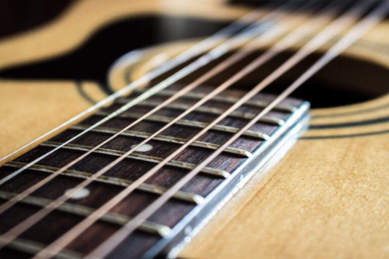 Primer plano de una guitarra con cuerdas y diapasón visible