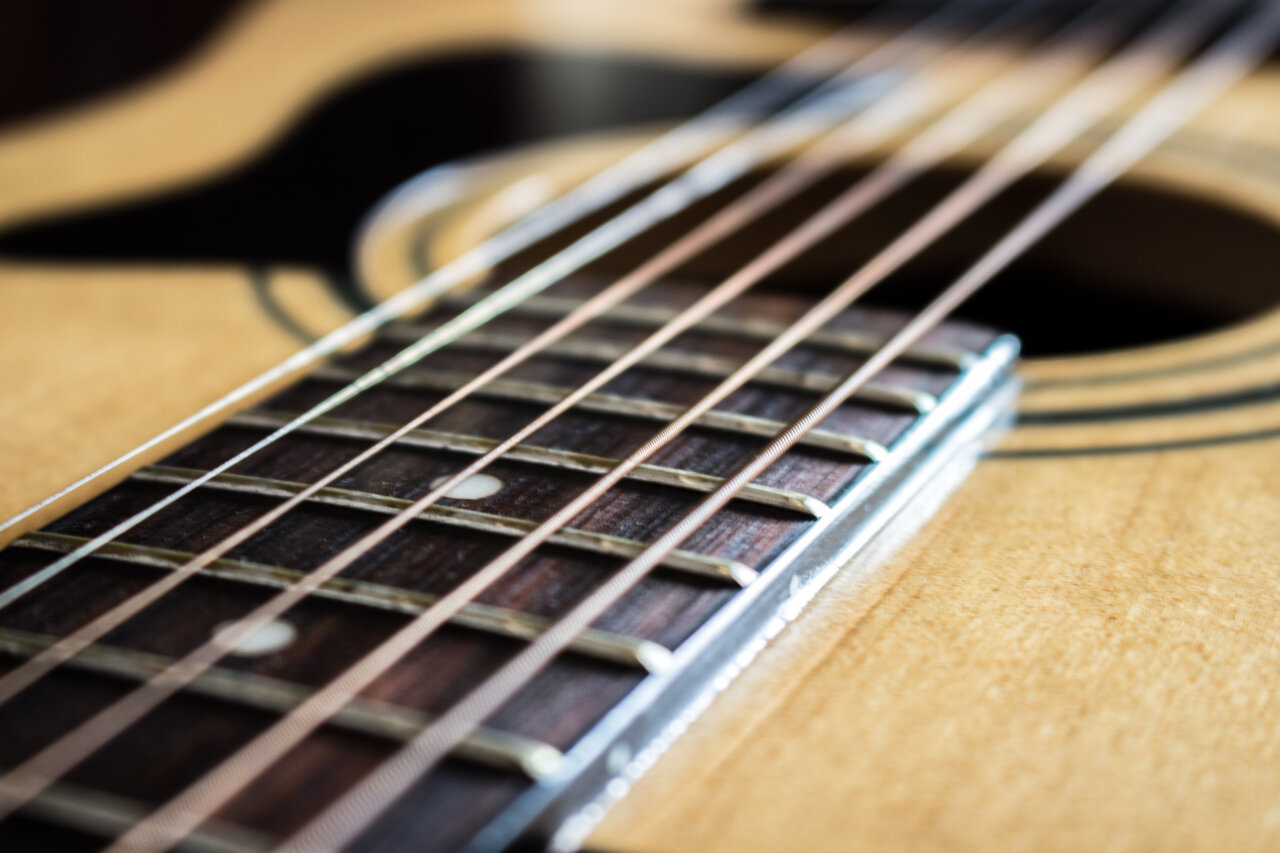 Primer plano de una guitarra con cuerdas y diapasón visible