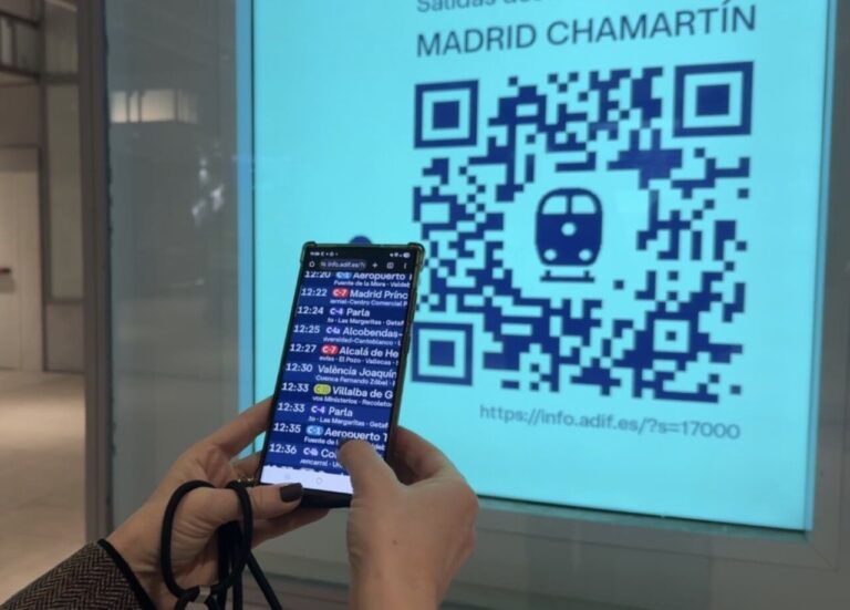 Persona usando un móvil para escanear un código QR en la estación de tren.
