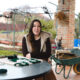 Mujer sonriente en un entorno rural con huerta y herramientas