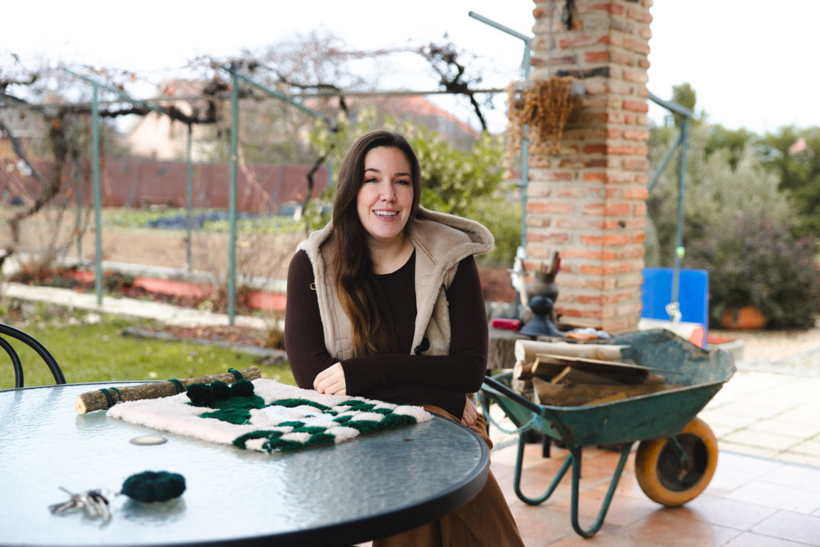 Mujer sonriente en un entorno rural con huerta y herramientas
