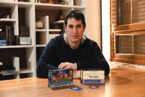 Un hombre sentado en una mesa con el juego Rastreo y cartas