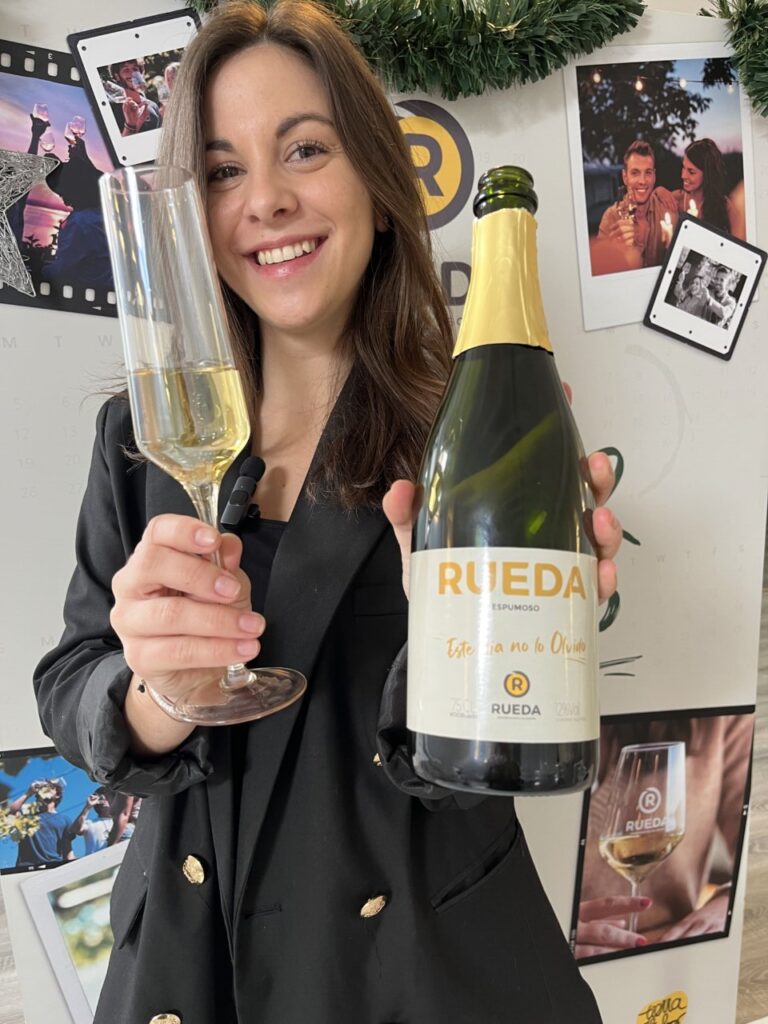 Mujer sosteniendo una botella de vino espumoso Rueda y una copa.