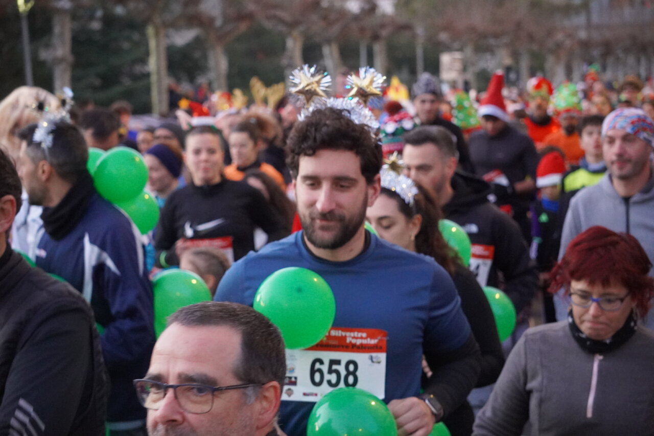 Participantes de la San Silvestre Palentina con globos verdes en la carrera.