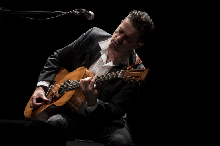 Santiago Auserón tocando la guitarra en un concierto acústico