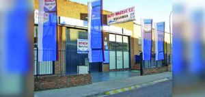 Fachada del taller Auto-Minerva en Palencia con banderas de servicio