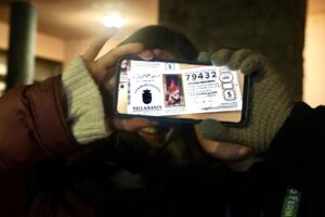 Dos personas sosteniendo un teléfono mostrando un boleto de lotería