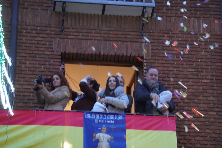 Personas celebrando un bautizo desde un balcón en Palencia