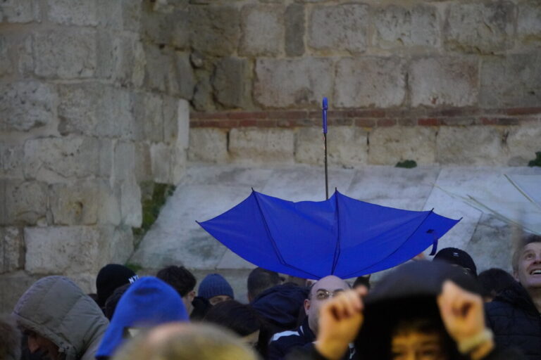 Grupo de personas en un bautizo con un paraguas azul
