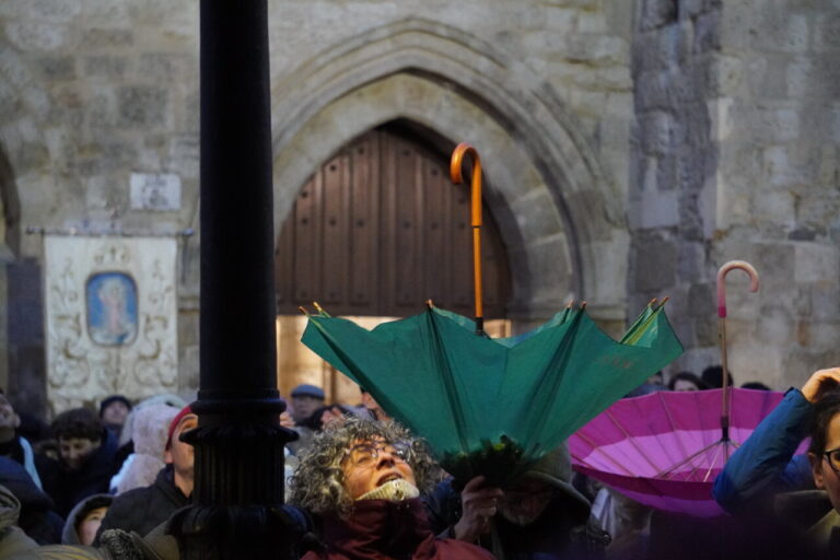 Personas con paraguas en una ceremonia de bautizo en San Miguel