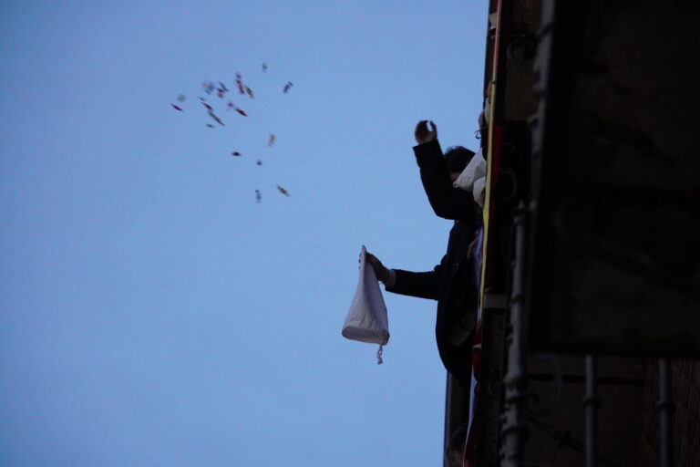 Persona lanzando objetos desde un balcón durante un bautizo