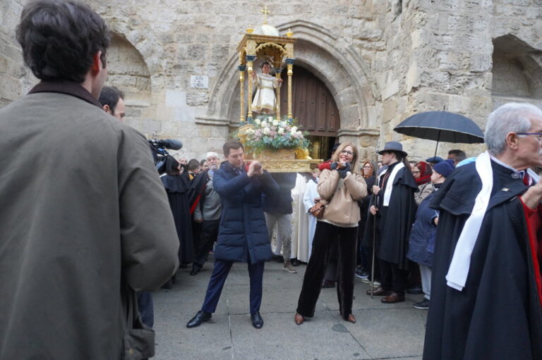 Celebración del bautizo del niño en San Miguel con asistentes y un santo en andas.