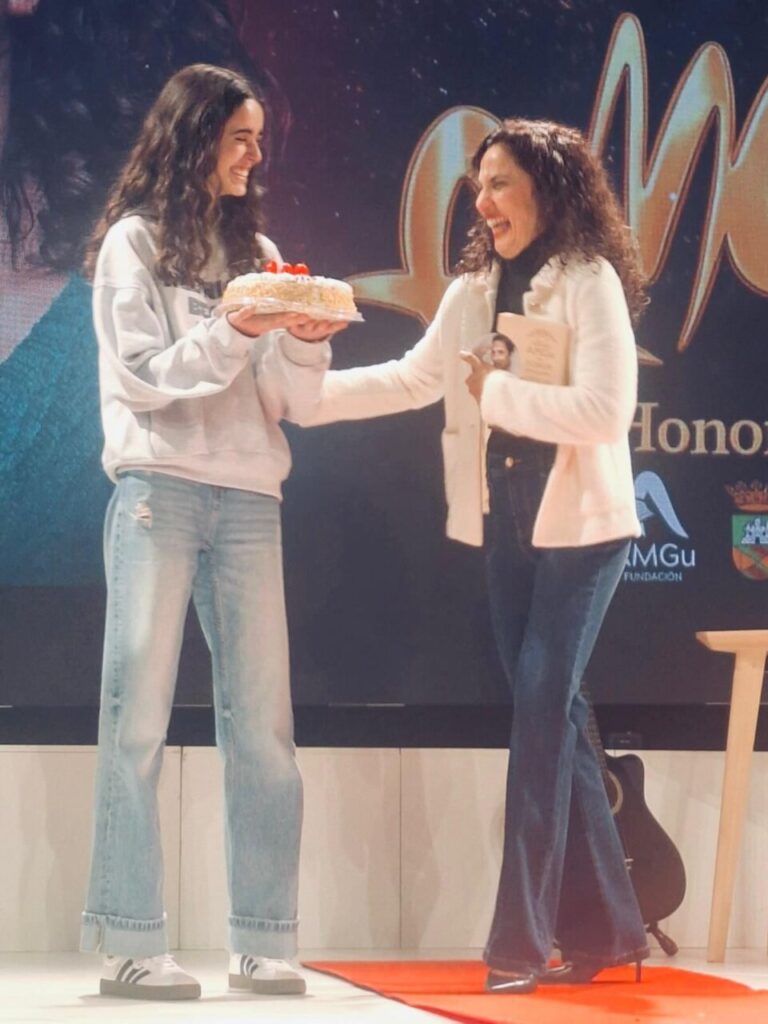 Toni Acosta recibiendo un premio con una tarta en el escenario