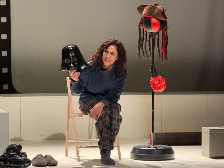 Toni Acosta en el escenario sosteniendo un casco de Darth Vader durante su actuación.