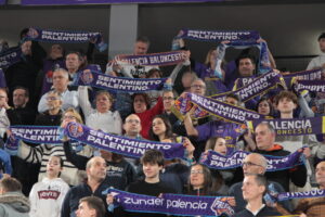 Aficionados del baloncesto sosteniendo bufandas en un partido