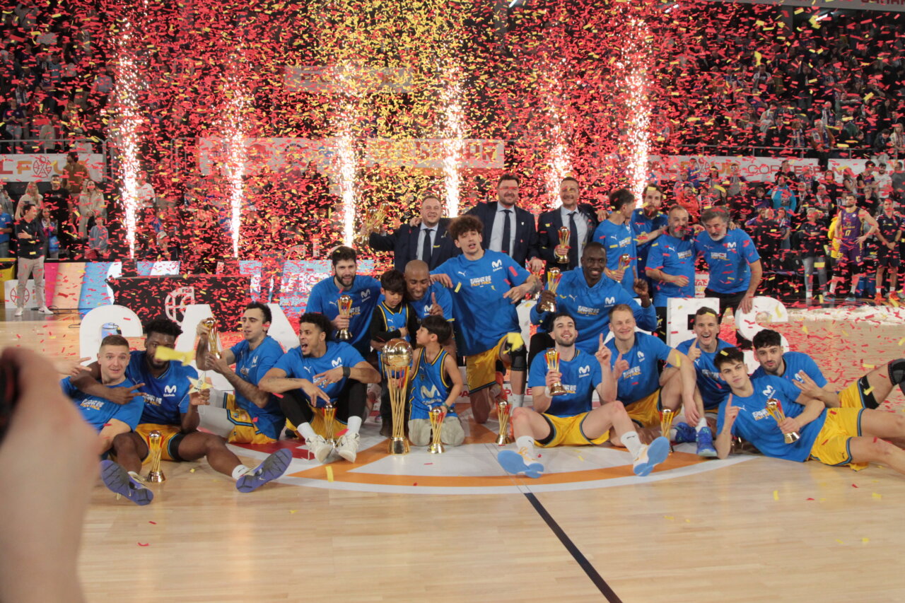 Jugadores del Palencia Basket celebrando la victoria en la Copa España con trofeos y confeti.